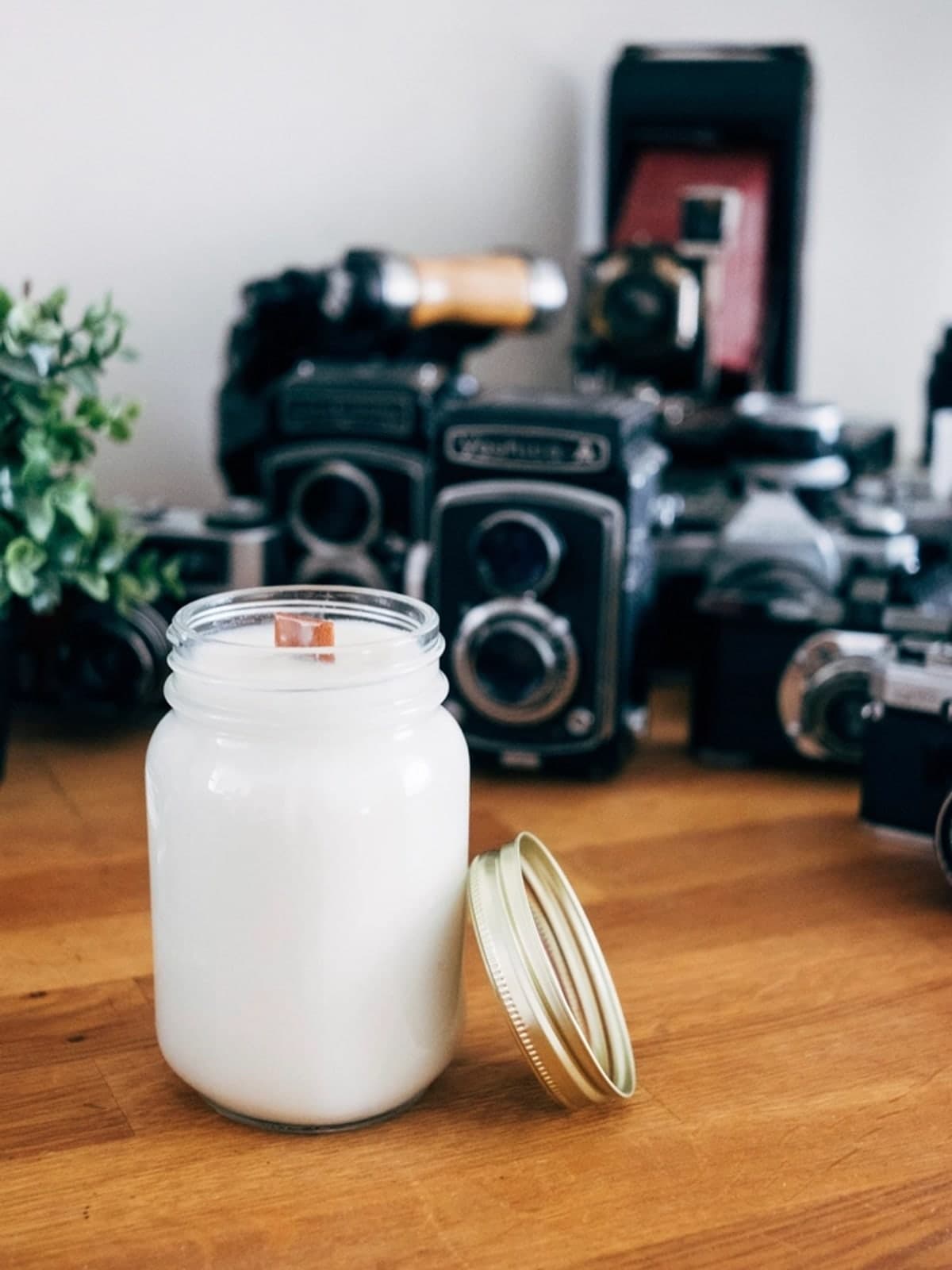 Foto original do celular: vela aromática em pote de vidro sobre uma mesa de madeira